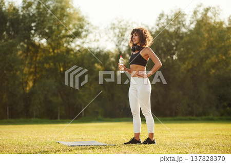 Break time, with bottle of water. Young fitness woman is on the field outdoors 137828370