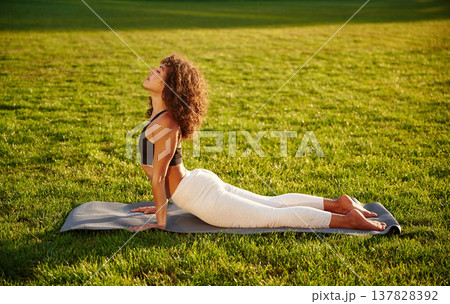 Spine yoga exercise. Young fitness woman is on the field outdoors Spine yoga exercise. Young fitness woman is on the field outdoors 137828392