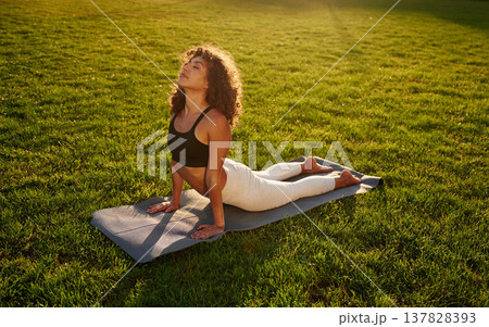 Spine yoga exercise. Young fitness woman is on the field outdoors 137828393