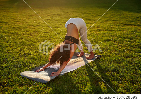 Doing yoga on a mat. Sportive woman doing fitness on the field 137828399