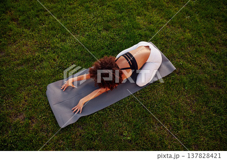 Doing yoga on a mat. Sportive woman doing fitness on the field 137828421