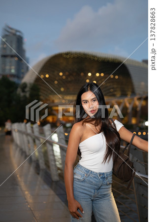 Asian tourist woman posing by the waterfront at Marina Bay Singapore during evening Asian tourist woman posing by the waterfront at Marina Bay Singapore during evening 137828663