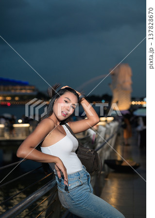 Asian tourist woman posing by the waterfront at Marina Bay Singapore during evening Asian tourist woman posing by the waterfront at Marina Bay Singapore during evening 137828670