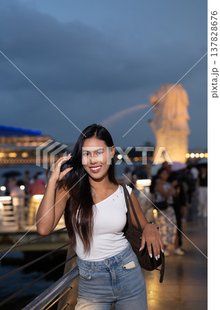 Asian tourist woman posing by the waterfront at Marina Bay Singapore during evening Asian tourist woman posing by the waterfront at Marina Bay Singapore during evening 137828676