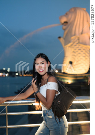 Asian tourist woman posing by the waterfront at Marina Bay Singapore during evening Asian tourist woman posing by the waterfront at Marina Bay Singapore during evening 137828677