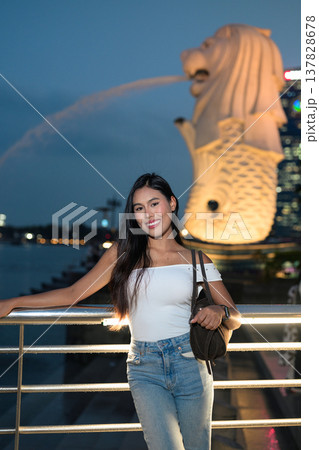 Asian tourist woman posing by the waterfront at Marina Bay Singapore during evening Asian tourist woman posing by the waterfront at Marina Bay Singapore during evening 137828678