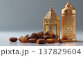 Luxurious Ramadan still life scene with golden lantern, ornate lamp, and dates on reflective surface, evoking warmth and celebration in peaceful, elegant setting 137829604