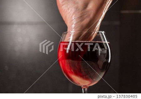 Foot fetish. A woman dips her toes in a glass of red wine. Foot fetish. A woman dips her toes in a glass of red wine. 137830405