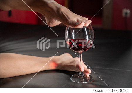 Foot fetish. A woman dips her toes in a glass of red wine. Foot fetish. A woman dips her toes in a glass of red wine. 137830723