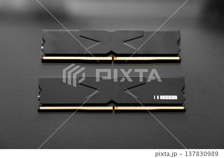 Black DDR5 RAM memory modules placed on a dark, glossy surface. RAM shortages on the market, rising prices, and increased demand driven by the growing need for AI training. 137830989