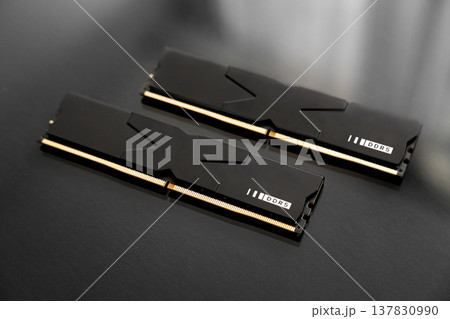 Black DDR5 RAM memory modules placed on a dark, glossy surface. RAM shortages on the market, rising prices, and increased demand driven by the growing need for AI training. Black DDR5 RAM memory modules placed on a dark, glossy surface. RAM shortages on the market, rising prices, and increased demand driven by the growing need for AI training. 137830990