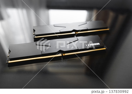 Black DDR5 RAM memory modules placed on a dark, glossy surface. RAM shortages on the market, rising prices, and increased demand driven by the growing need for AI training. 137830992