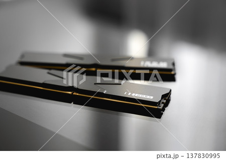 Black DDR5 RAM memory modules placed on a dark, glossy surface. RAM shortages on the market, rising prices, and increased demand driven by the growing need for AI training. Black DDR5 RAM memory modules placed on a dark, glossy surface. RAM shortages on the market, rising prices, and increased demand driven by the growing need for AI training. 137830995