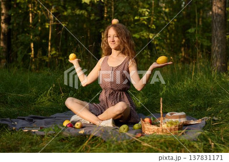 Tranquil scene of woman relaxing with apples in forest at sunset Tranquil scene of woman relaxing with apples in forest at sunset 137831171