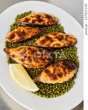 Fresh baked mussels served with vibrant peas and citrus wedge Fresh baked mussels served with vibrant peas and citrus wedge 137831180