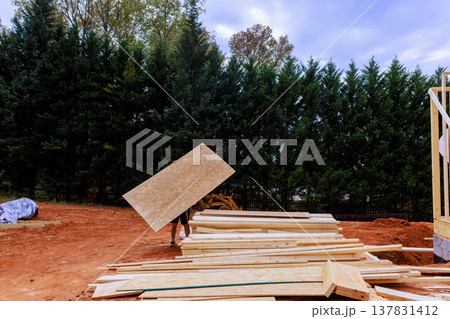 Contractor is moving wooden plywood at construction site 137831412