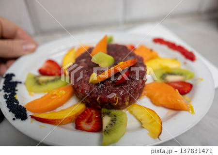 Gourmet red tuna tartare prepared with fresh strawberries, kiwi, peaches, orange zest, and black caviar, creating a colorful and healthy seafood appetizer Gourmet red tuna tartare prepared with fresh strawberries, kiwi, peaches, orange zest, and black caviar, creating a colorful and healthy seafood appetizer 137831471
