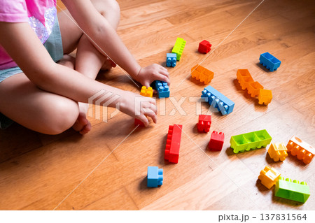 Child playing with colorful building blocks on wooden floor Child playing with colorful building blocks on wooden floor 137831564