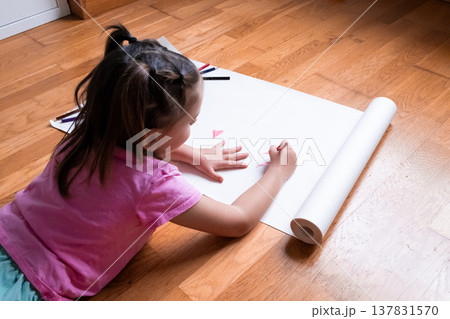 Young asian girl drawing on white paper with pencils on wooden floor Young asian girl drawing on white paper with pencils on wooden floor 137831570
