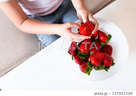 Female child enjoying fresh strawberries from a bowl Female child enjoying fresh strawberries from a bowl 137831580