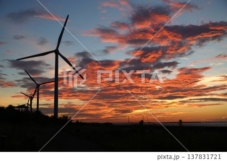 鮮やかな夕焼け空と風力発電の風車のシルエット 鮮やかな夕焼け空と風力発電の風車のシルエット 137831721