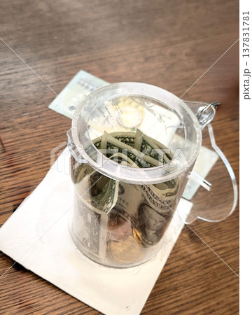 Tips in the form of American dollars in a clear plastic cup Tips in the form of American dollars in a clear plastic cup 137831781