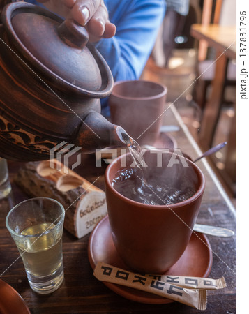 【ウクライナ】西部リヴィウのレストランで陶器のポットでコップにお茶を注いでもらう様子 137831796