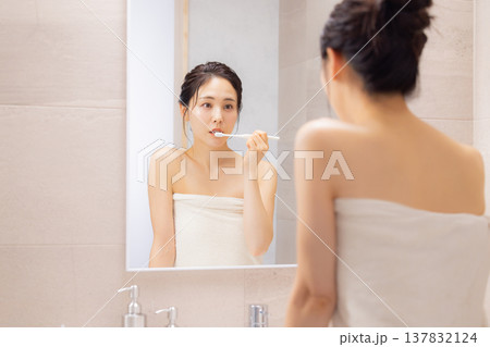 バスルームで歯磨きをする若い女性 バスルームで歯磨きをする若い女性 137832124