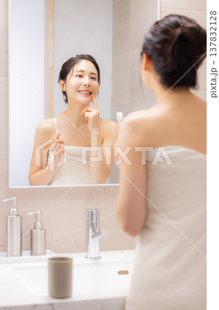 バスルームで歯磨きをする若い女性 バスルームで歯磨きをする若い女性 137832128
