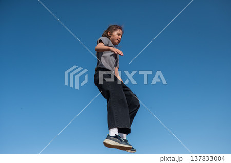 A girl jumps on an outdoor trampoline. 137833004