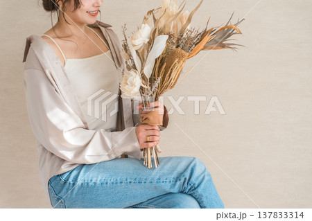 スワッグ,花束を持つ椅子に座るおしゃれなデニム姿の女性モデル スワッグ,花束を持つ椅子に座るおしゃれなデニム姿の女性モデル 137833314