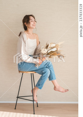 スワッグ,花束を持つ椅子に座るおしゃれなデニム姿の女性モデル 137833319