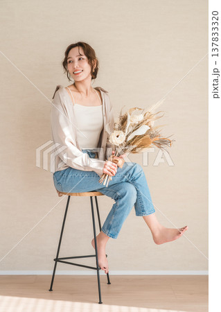 スワッグ,花束を持つ椅子に座るおしゃれなデニム姿の女性モデル スワッグ,花束を持つ椅子に座るおしゃれなデニム姿の女性モデル 137833320
