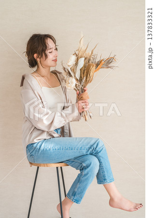 スワッグ,花束を持つ椅子に座るおしゃれなデニム姿の女性モデル スワッグ,花束を持つ椅子に座るおしゃれなデニム姿の女性モデル 137833321