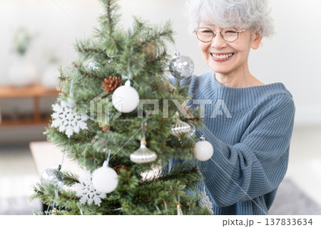 クリスマスツリーのオーナメントを飾るシニア女性 クリスマスツリーのオーナメントを飾るシニア女性 137833634