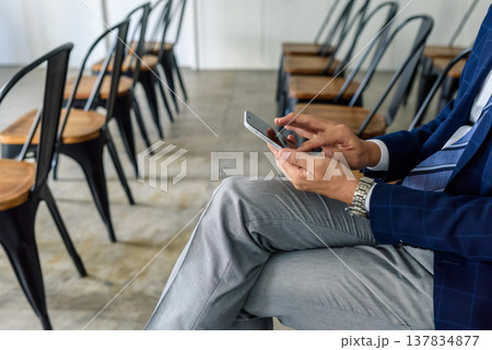 会議前の男性がスマートフォンを操作 会議前の男性がスマートフォンを操作 137834877