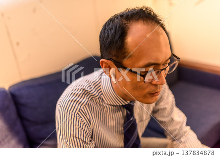 イヤホンで通話する中年の男性 イヤホンで通話する中年の男性 137834878