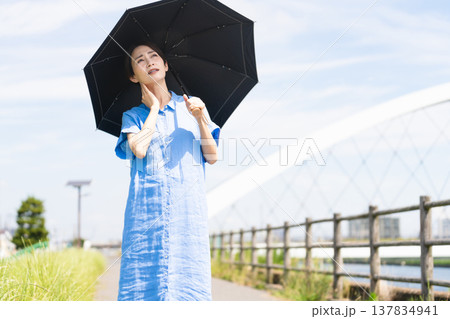 日傘をさして散歩する若い女性　ライフスタイルイメージ 137834941