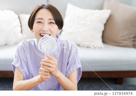 ハンドファンを使う若い女性　ライフスタイルイメージ 137834974