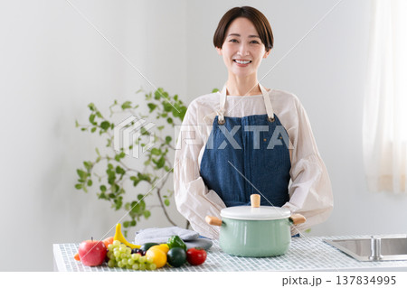 エプロン姿で料理する若い女性　ライフスタイルイメージ 137834995