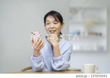 スマートフォンの画面を見る笑顔のアラカンの女性 スマートフォンの画面を見る笑顔のアラカンの女性 137835041