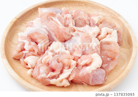 木製のお皿に載せた生の鶏もも肉のぶつ切り 137835093