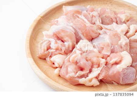 木製のお皿に載せた生の鶏もも肉のぶつ切り 137835094