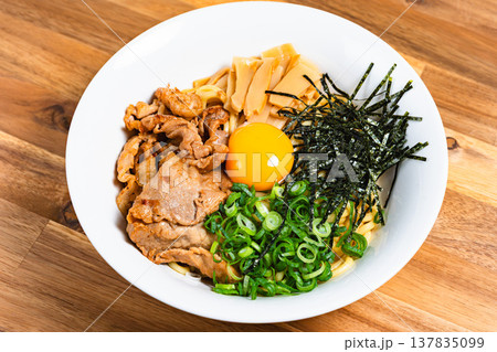 豚肉と生卵をのせた油そば 木製テーブルの上の手作りまぜそば 豚肉と生卵をのせた油そば 木製テーブルの上の手作りまぜそば 137835099