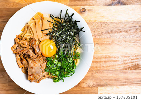 豚肉と生卵をのせた油そば 木製テーブルの上の手作りまぜそば 豚肉と生卵をのせた油そば 木製テーブルの上の手作りまぜそば 137835101
