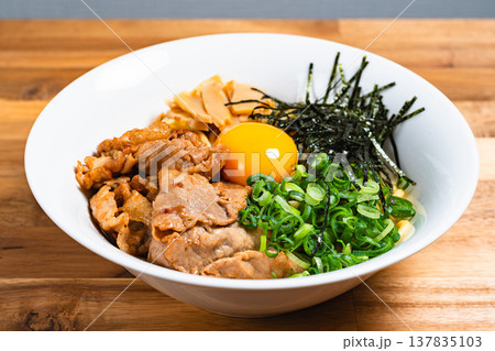 豚肉と生卵をのせた油そば 木製テーブルの上の手作りまぜそば 豚肉と生卵をのせた油そば 木製テーブルの上の手作りまぜそば 137835103