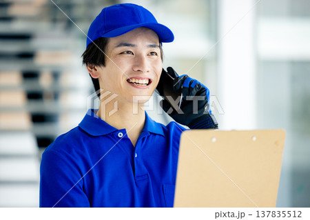 倉庫でスマホを持つ作業員の男性 倉庫でスマホを持つ作業員の男性 137835512