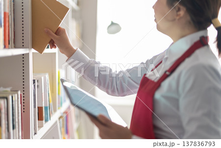 書店員が本棚から本を取る 書店員が本棚から本を取る 137836793