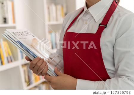 赤いエプロンの店員が雑誌を持つ 137836798