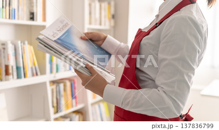 科学雑誌を手に取る女性店員 科学雑誌を手に取る女性店員 137836799
